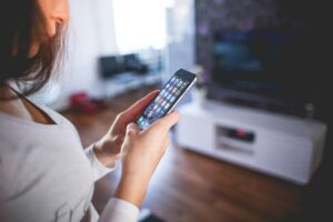 Woman using her smartphone highlighting modern technology and communication in a cozy home setting.